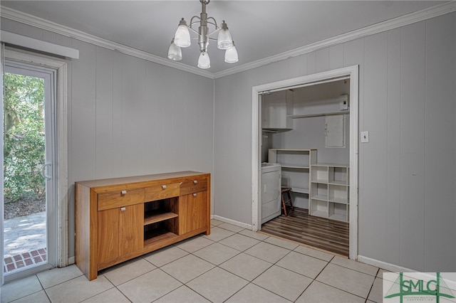 interior space featuring washer / clothes dryer, light tile patterned floors, an inviting chandelier, wood walls, and crown molding