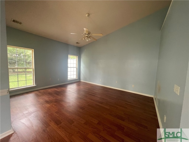 unfurnished room with vaulted ceiling, ceiling fan, a healthy amount of sunlight, and dark hardwood / wood-style flooring