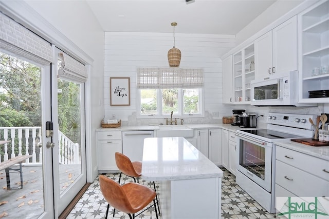 kitchen featuring white appliances, tasteful backsplash, sink, hanging light fixtures, and white cabinetry