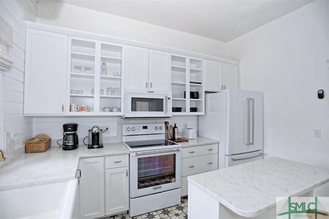 kitchen featuring decorative backsplash, white cabinets, light stone counters, sink, and white appliances