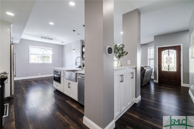 kitchen with stainless steel appliances, white cabinetry, dark wood-type flooring, and sink