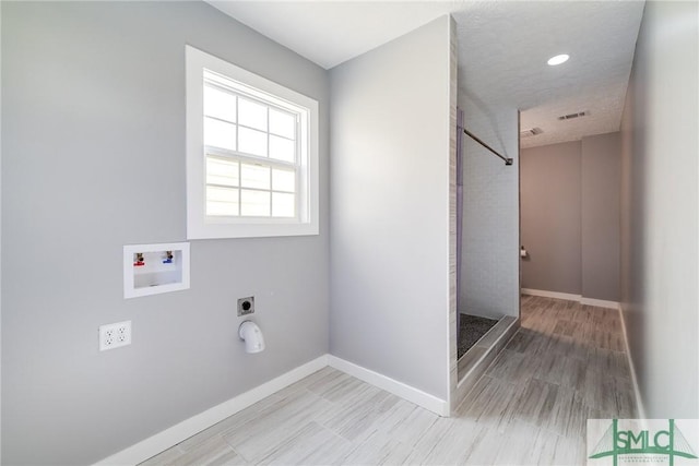 laundry area with electric dryer hookup, hookup for a washing machine, and light hardwood / wood-style flooring