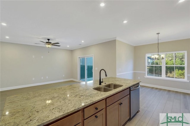 kitchen featuring decorative light fixtures, sink, stainless steel dishwasher, light stone countertops, and light wood-type flooring