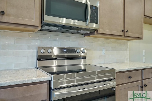 kitchen featuring light stone counters, decorative backsplash, and stainless steel appliances