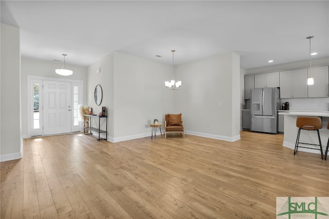 foyer entrance with light hardwood / wood-style floors and an inviting chandelier