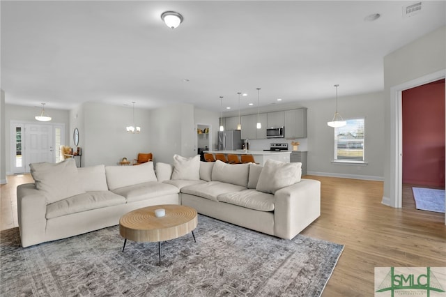 living room with a chandelier and light wood-type flooring