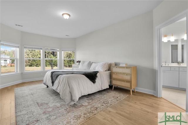 bedroom featuring light hardwood / wood-style floors, sink, and connected bathroom