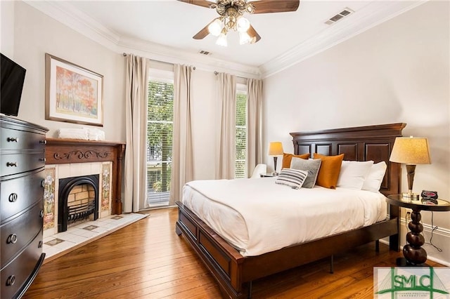 bedroom featuring crown molding, access to outside, a tile fireplace, and light wood-type flooring