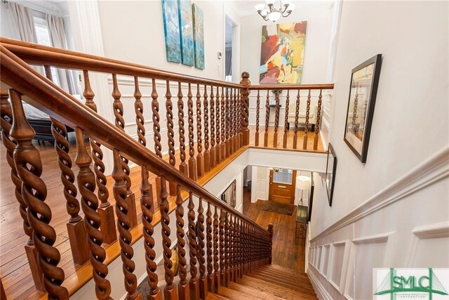 stairway with hardwood / wood-style flooring and a chandelier