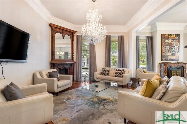 living room featuring crown molding, hardwood / wood-style floors, a notable chandelier, and a large fireplace