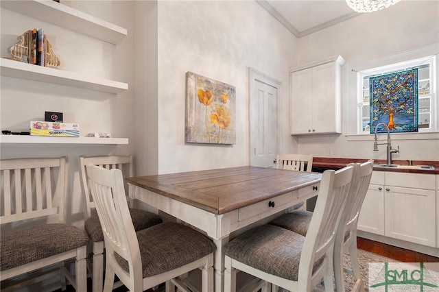 dining space with sink, crown molding, and hardwood / wood-style flooring