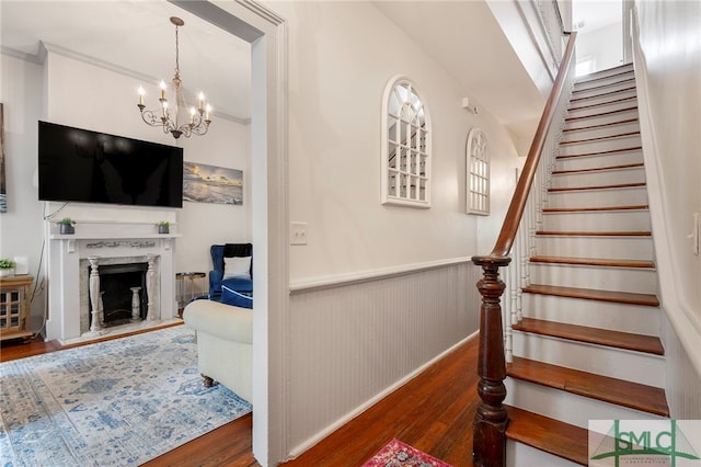 stairway with a notable chandelier, hardwood / wood-style floors, wood walls, and a high end fireplace