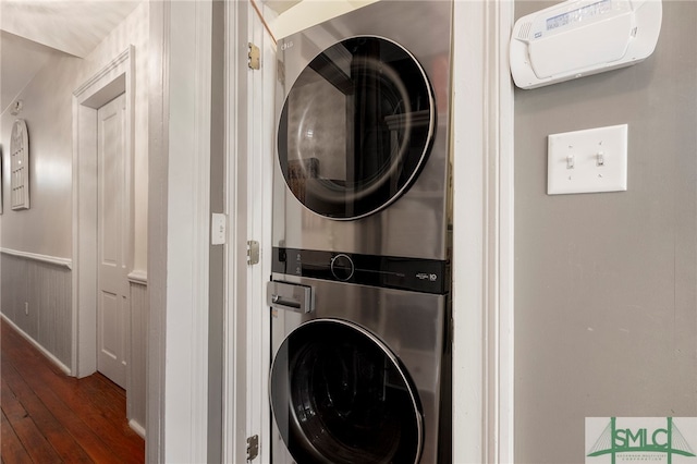 laundry area featuring stacked washer / dryer and dark hardwood / wood-style flooring