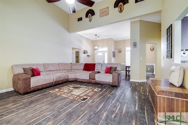 living room with ceiling fan, dark hardwood / wood-style flooring, a towering ceiling, and ornamental molding