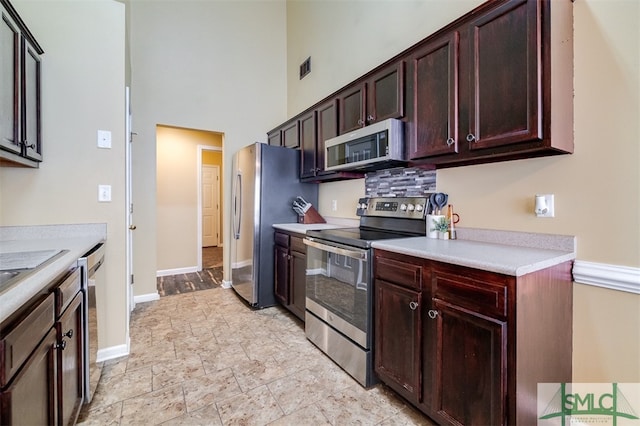 kitchen featuring a towering ceiling and stainless steel appliances