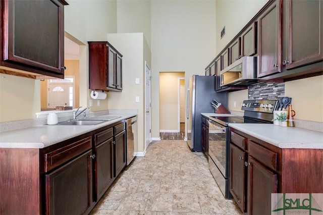 kitchen with sink, a towering ceiling, and stainless steel appliances