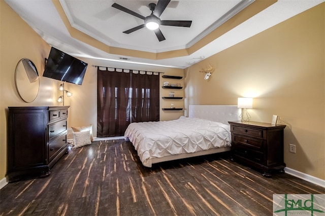 bedroom with a tray ceiling, ceiling fan, crown molding, and dark wood-type flooring