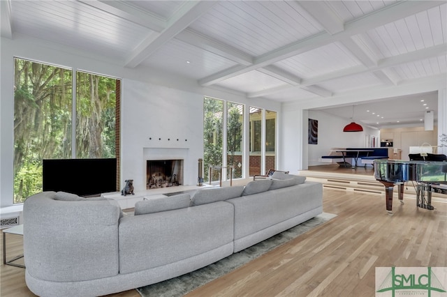 living room with light wood-type flooring, coffered ceiling, beam ceiling, and plenty of natural light