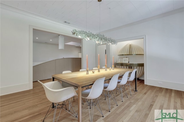 dining area with crown molding and light hardwood / wood-style floors