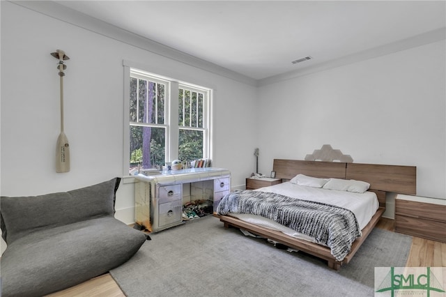 bedroom with ornamental molding and hardwood / wood-style flooring