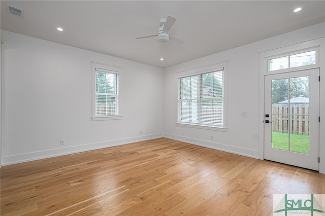 empty room featuring ceiling fan, plenty of natural light, and light wood-type flooring