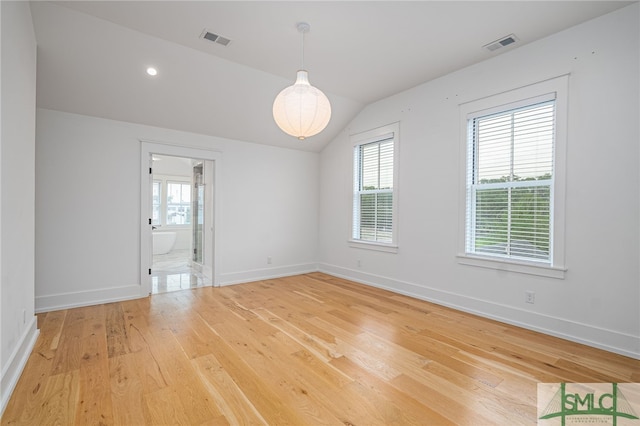 spare room with hardwood / wood-style floors, vaulted ceiling, and a healthy amount of sunlight