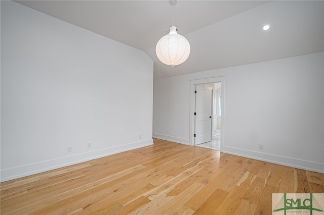 unfurnished room featuring lofted ceiling and hardwood / wood-style floors