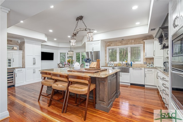 kitchen featuring a center island, hardwood / wood-style floors, white cabinetry, a wealth of natural light, and wine cooler