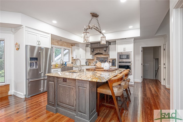 kitchen featuring sink, a center island, white cabinetry, appliances with stainless steel finishes, and light stone counters