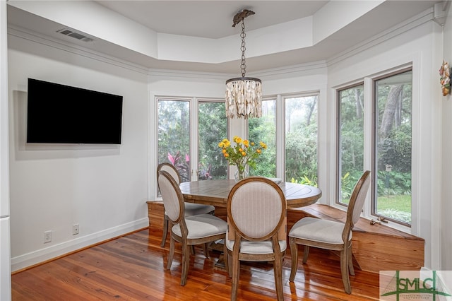 dining space with a wealth of natural light, hardwood / wood-style floors, a tray ceiling, and a chandelier