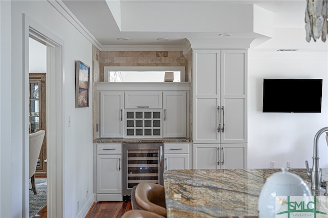 bar with white cabinets, light stone counters, beverage cooler, and dark hardwood / wood-style floors