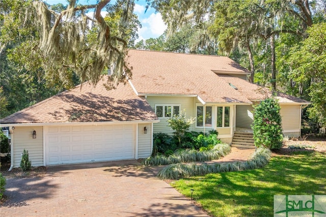 single story home featuring roof with shingles, decorative driveway, and a garage