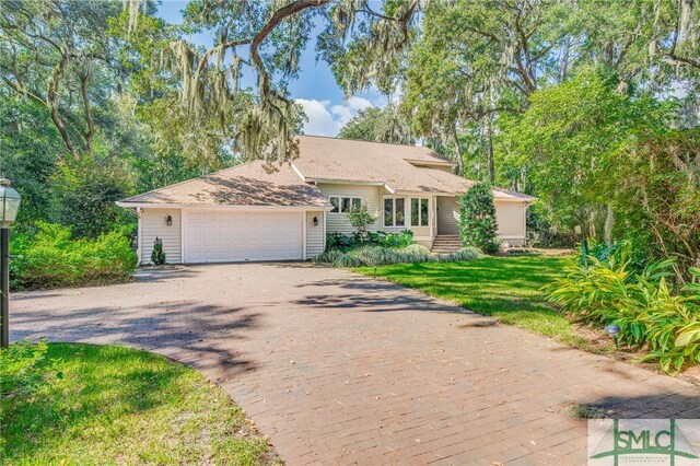 single story home with an attached garage, decorative driveway, and a front yard