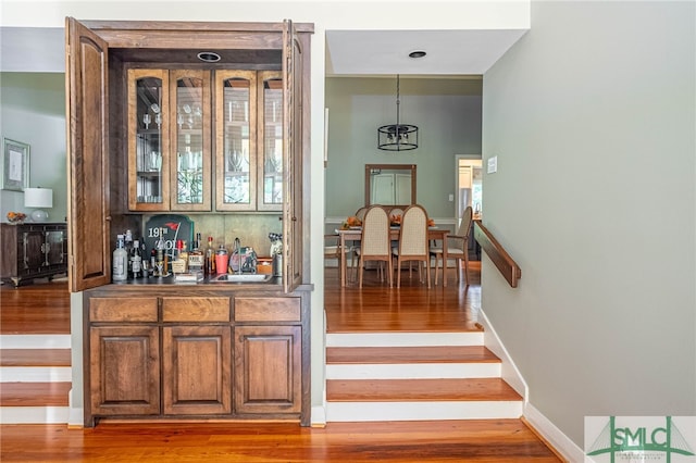 bar featuring hardwood / wood-style floors, tasteful backsplash, sink, and pendant lighting