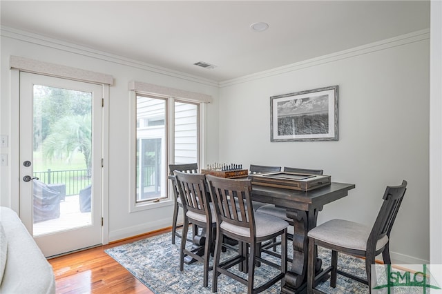 dining space featuring baseboards, light wood-style flooring, visible vents, and crown molding