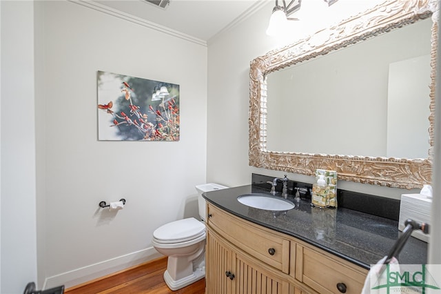 bathroom with wood finished floors, vanity, baseboards, toilet, and ornamental molding