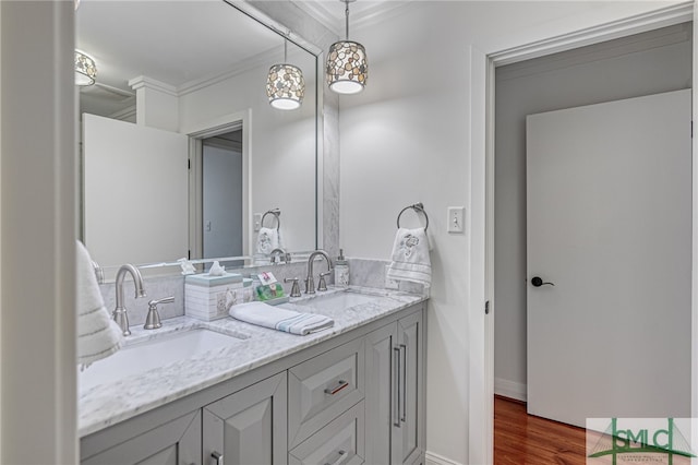 bathroom with double vanity, wood finished floors, ornamental molding, and a sink