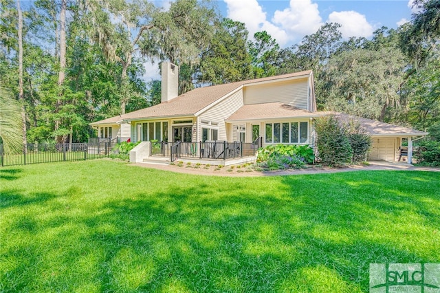 rear view of house with fence, a lawn, a chimney, and a deck