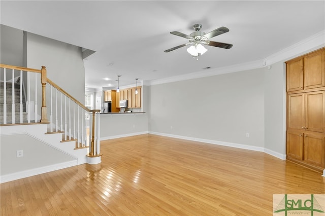 unfurnished living room featuring ceiling fan, ornamental molding, and light wood-type flooring