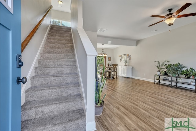 stairs featuring hardwood / wood-style flooring, plenty of natural light, and ceiling fan with notable chandelier