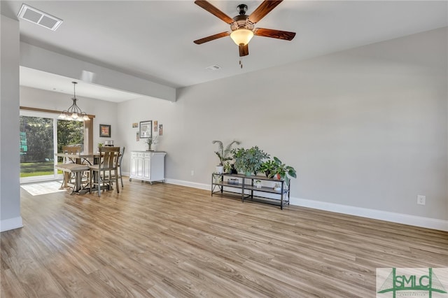 unfurnished room with ceiling fan with notable chandelier and light wood-type flooring