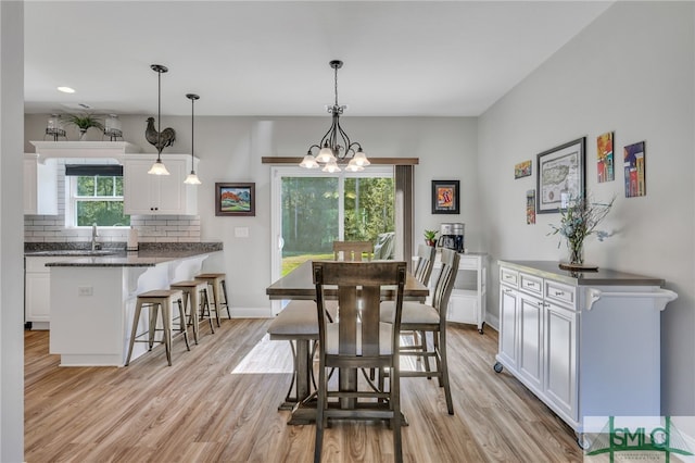 dining room featuring sink, a notable chandelier, light hardwood / wood-style floors, and plenty of natural light