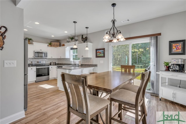 dining room featuring light hardwood / wood-style floors, a healthy amount of sunlight, sink, and a chandelier