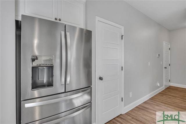 kitchen featuring white cabinets, light hardwood / wood-style flooring, and stainless steel fridge