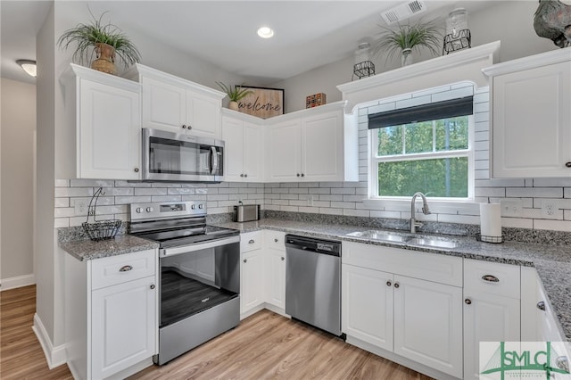 kitchen with sink, white cabinets, stainless steel appliances, and backsplash