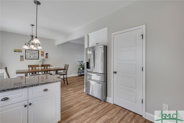 kitchen featuring hanging light fixtures, stainless steel refrigerator with ice dispenser, light wood-type flooring, a chandelier, and white cabinets