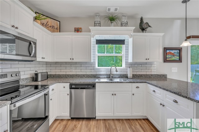 kitchen featuring hanging light fixtures, sink, white cabinetry, appliances with stainless steel finishes, and light hardwood / wood-style floors