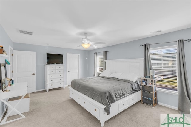 bedroom with multiple windows, light colored carpet, and ceiling fan