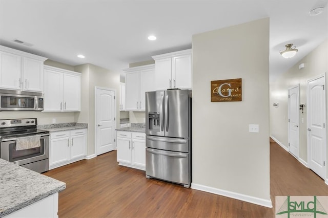 kitchen featuring white cabinetry, stainless steel appliances, light stone countertops, and dark hardwood / wood-style flooring