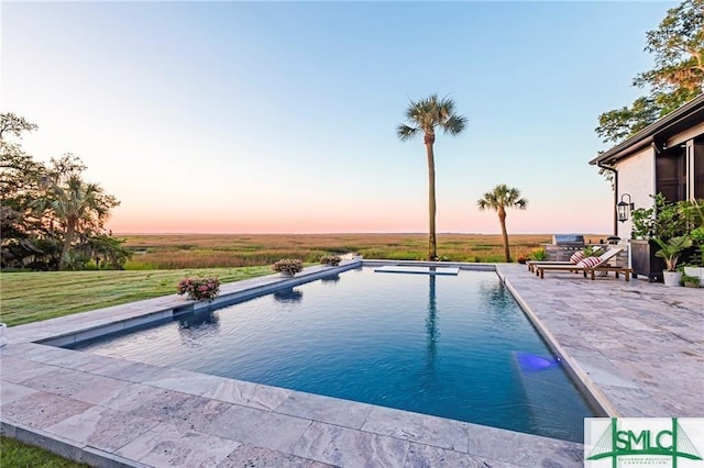 pool at dusk featuring a patio